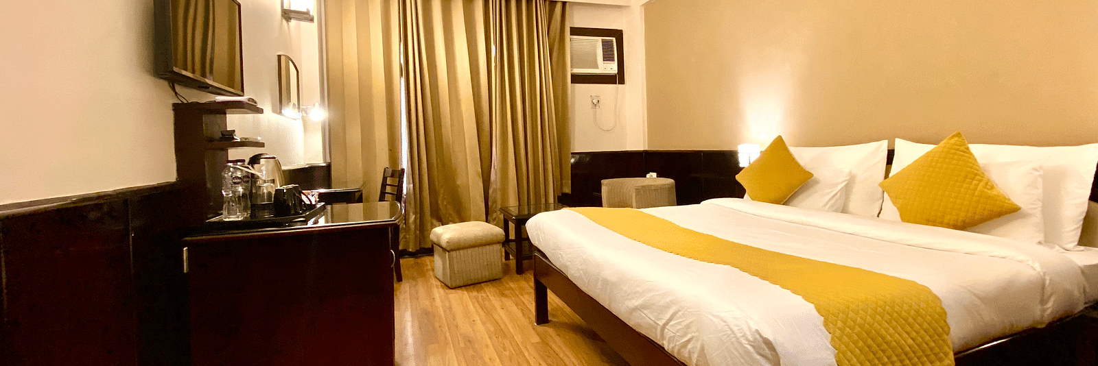 A spacious hotel room with a king size bed, a desk, a chair, and a flat-screen TV.  | DLS Park Grace, Haridwar